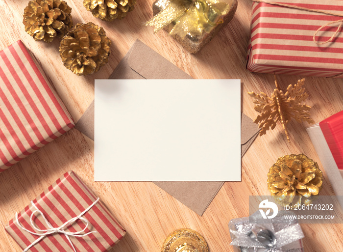木桌背景上有金色松果圣诞和礼品盒装饰的实物纸卡片。