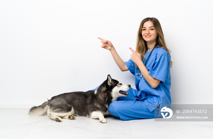 兽医带着西伯利亚哈士奇犬坐在地板上，手指指向侧面