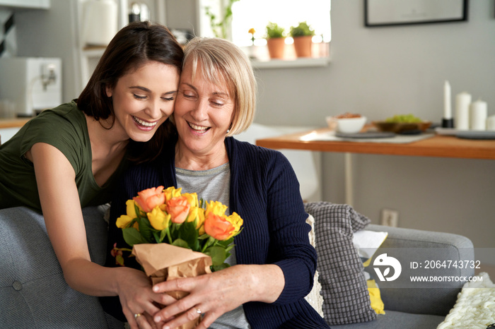 Happy daughter giving flowers to her mother