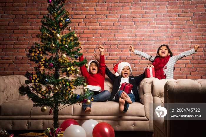 Indian kids celebrating christmas - cute little Indian kids playing, laughing and having fun with gi