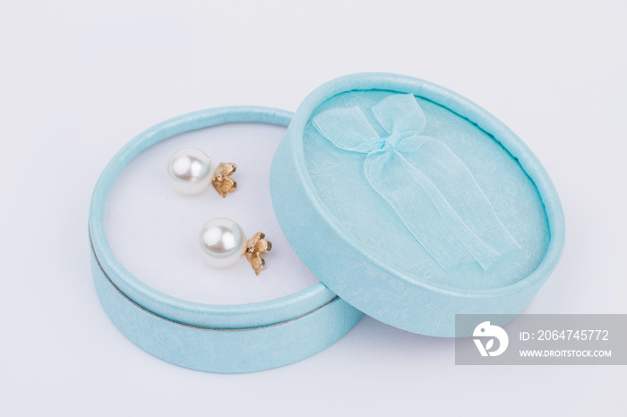 Golden earrings in jewelry box. Blue gift box with pearl earrings on light background. Beautiful gif