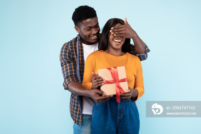 Happy black man making surprise for his woman giving box