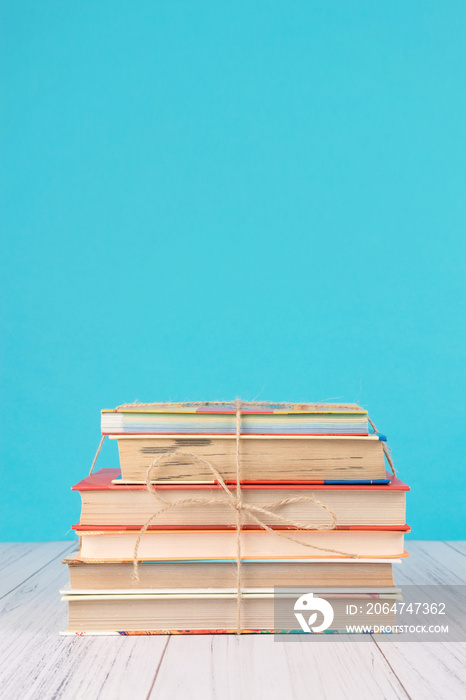 一堆书和粉红色的心。蓝色背景上有黄麻丝带蝴蝶结作为礼物的书。教育回来了