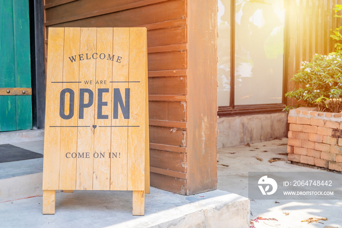 Closeup Wooden sign placed in front of the shop is labeled WELCOME Come on in Were OPEN