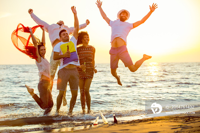 一群快乐的年轻人在美丽的夏日日落下在海滩上跳舞