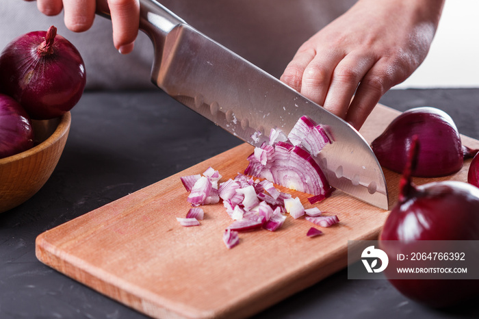 young woman in a gray aprons cuts red onion