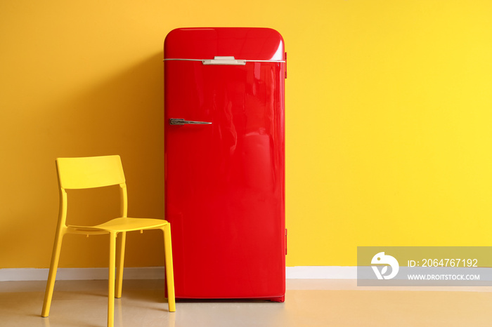 Red fridge and chair near yellow wall