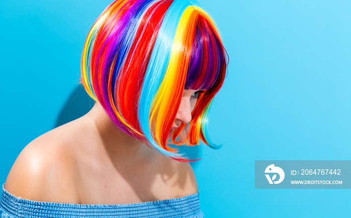 Beautiful woman in a colorful wig on a blue background