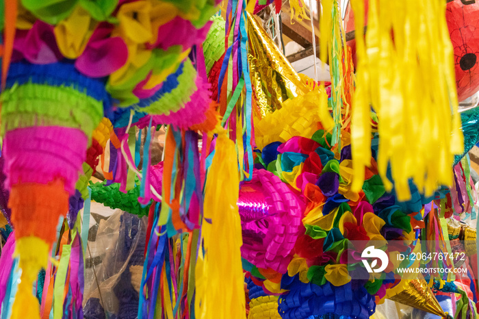 Colorful pinatas with paper stripes hanging inside a market