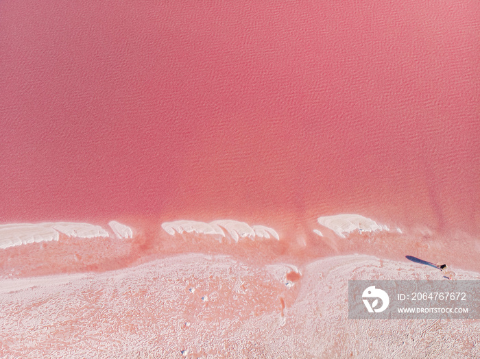 The surface of a pink lake with islands of salt. Top-down view.