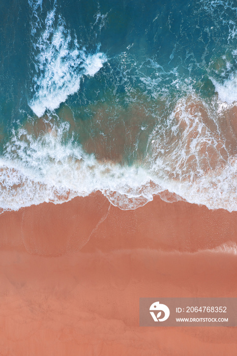 Aerial view of pink beach and blue ocean wave.