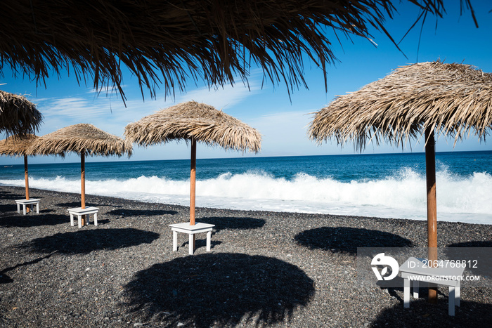 希腊圣托里尼空旷海滩上的雨伞。田园诗般的旅行背景