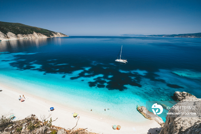 Beach leisure activity. Fteri bay, Kefalonia, Greece. White catamaran yacht in clear blue sea water.