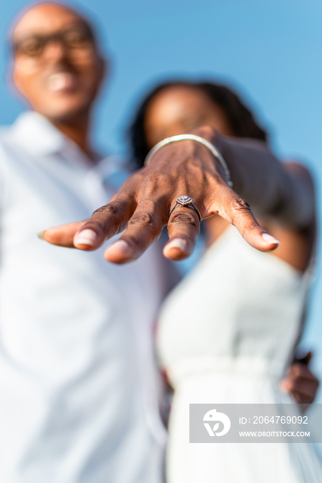 Young black woman showing of her engagement ring while standing beside fiancé, selective focus on ri