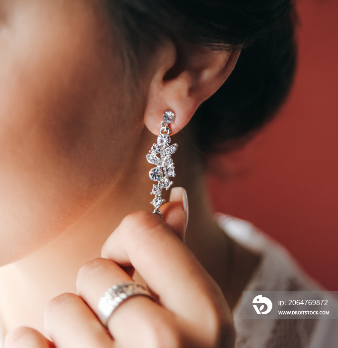 Bride is wearing jewellery. White artificial diamond earring. Elegant style. Wedding day.