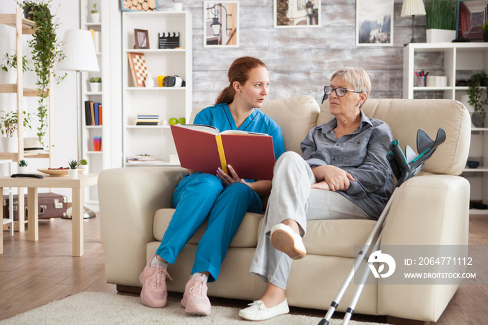 Female nursing reading a book for a senior woman