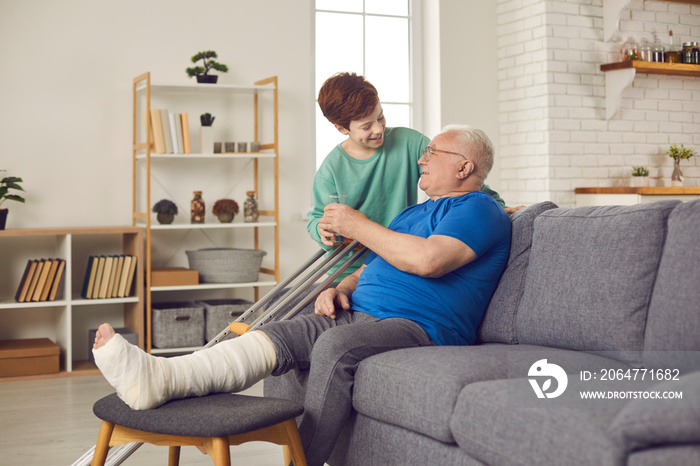 Family members take good care of senior man with broken leg. Little child helps injured grandfather 