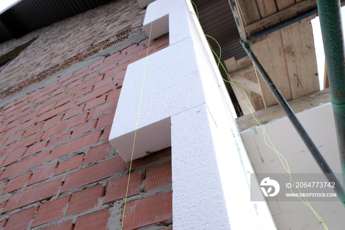 Close-up detail of brick house wall with rigid styrofoam insulation sheet. Modern technology of cons