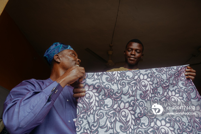 Father and son stretching out fabric while smiling