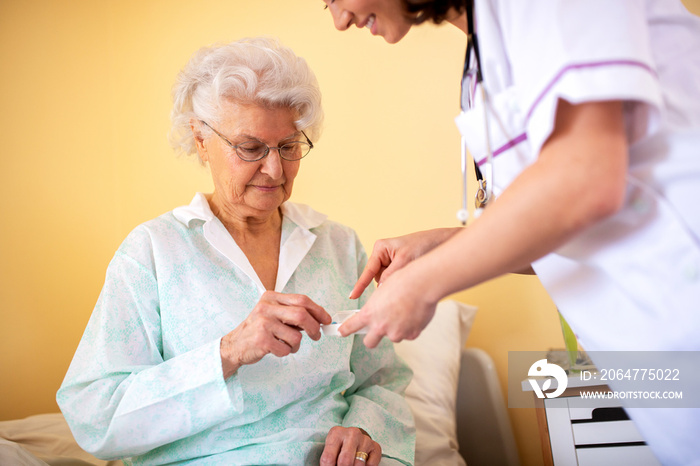 熟练的护理机构医生向老年女性住户解释她应该服用哪些药物