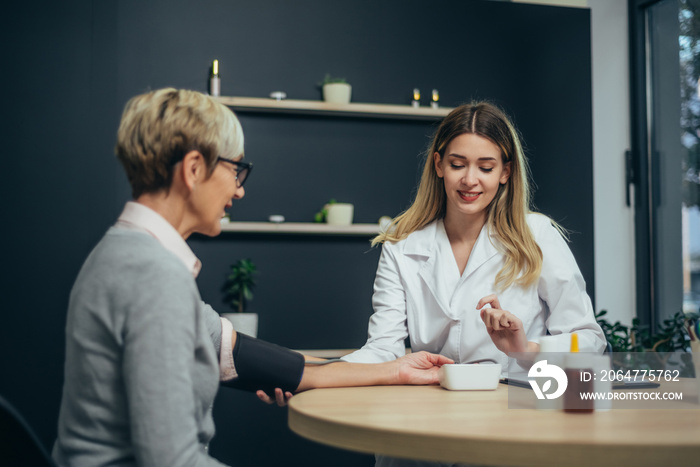 Doctor measuring blood pressure of a senior woman patient