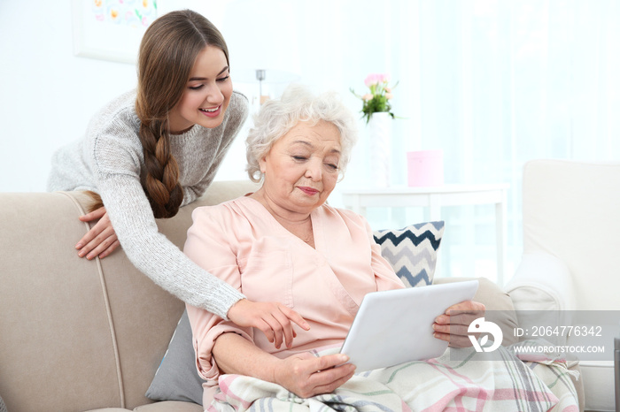 Beautiful girl with grandmother using tablet at home