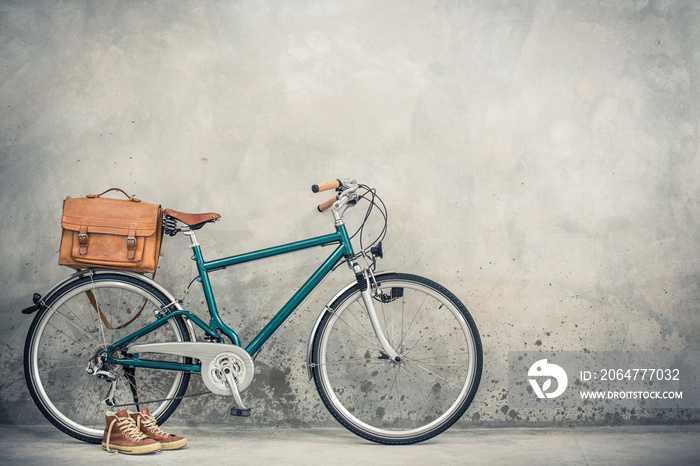 复古自行车，配旧皮革邮筒包和旧运动鞋，正面混凝土墙背景。复古