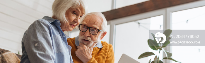 thoughtful senior husband looking at wife at home on blurred background, banner