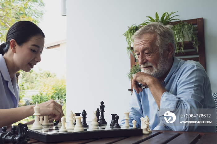 senior man happiness and nurse, playing chess at balcony near garden at nursing home together