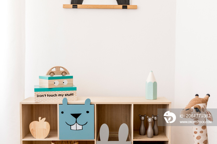Stylish scandinavian child room with wooden cabinet, toys, boxes and plush teddy. White walls, Minim