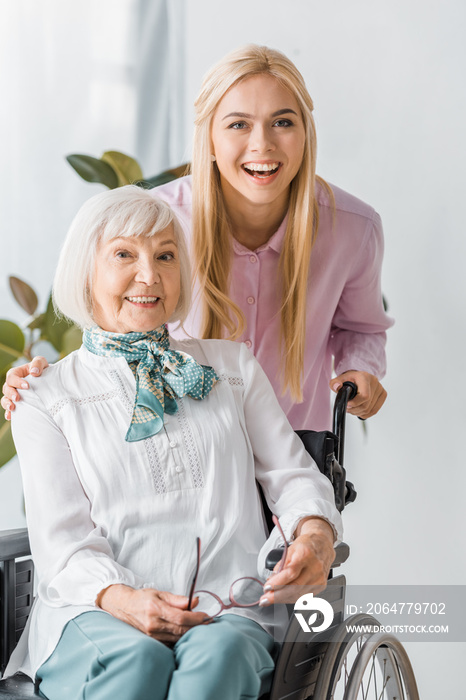 young and senior women in wheelchair smiling and looking at camera