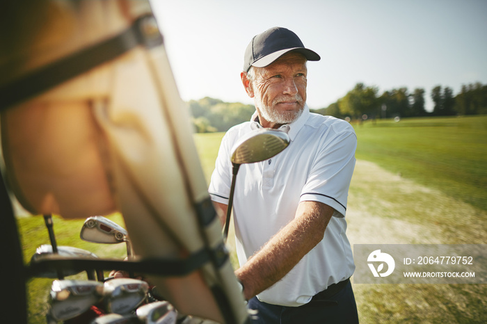 Senior man preparing to play golf on a sunny day