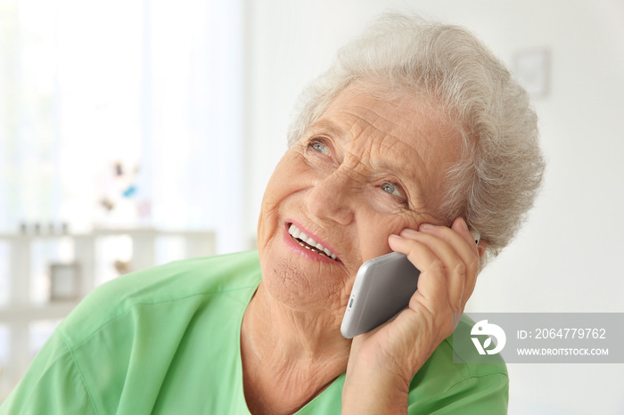 Elderly woman speaking on cell phone at home