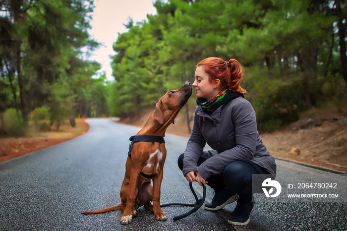 Portrait of happy teenage girl and Rhodesian ridgeback dog . Dog giving girl sweet kiss lick. Love a