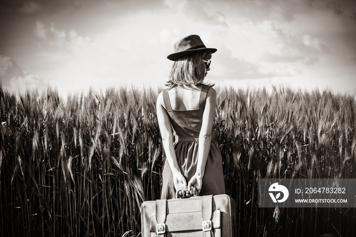 photo of young beautiful woman with suitcase in the field. Image in black and white color style