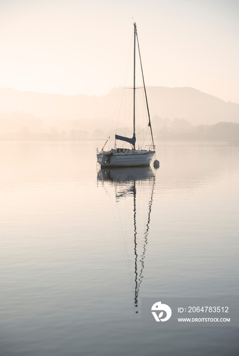 Stunning unplugged fine art landscape image of sailing yacht sitting still in calm lake water in Lak