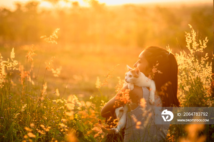 Vintage photo of young woman with cat on field in sunset