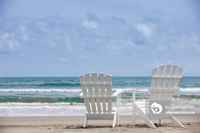 Empty white wooden chairs at a paradisiac beach on the tropics in a beautiful sunny day