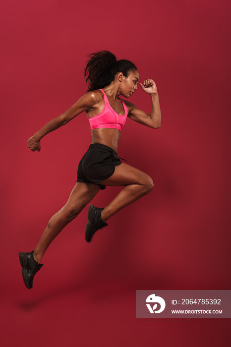 Runner concentrated strong young african sports woman posing isolated over red wall background runni