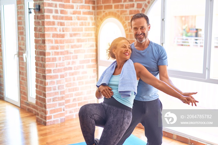 Middle age beautiful sporty couple smiling happy. Standing with smile on face hugging at gym