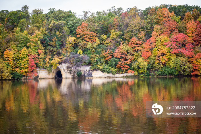 密西西比河上的水平图像，岸边有五颜六色的秋叶，倒影在水中。