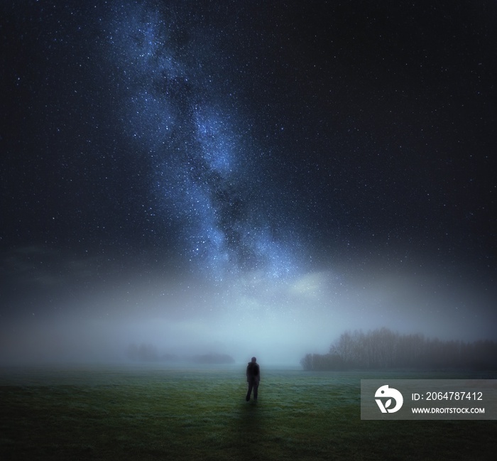 Dreamy surreal landscape with starry night sky and man silhouette