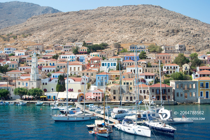 The colourful harbour at the the beautiful Greek island of Chalki.  Classical architecture rises fro