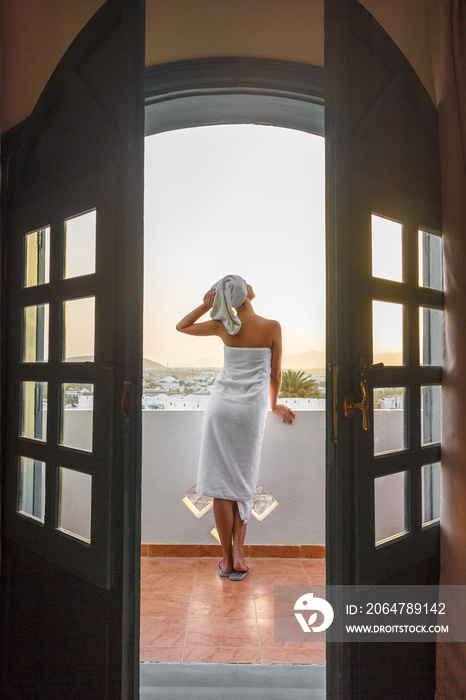 一个穿着白毛巾的女人站在酒店房间里俯瞰群山的露台上