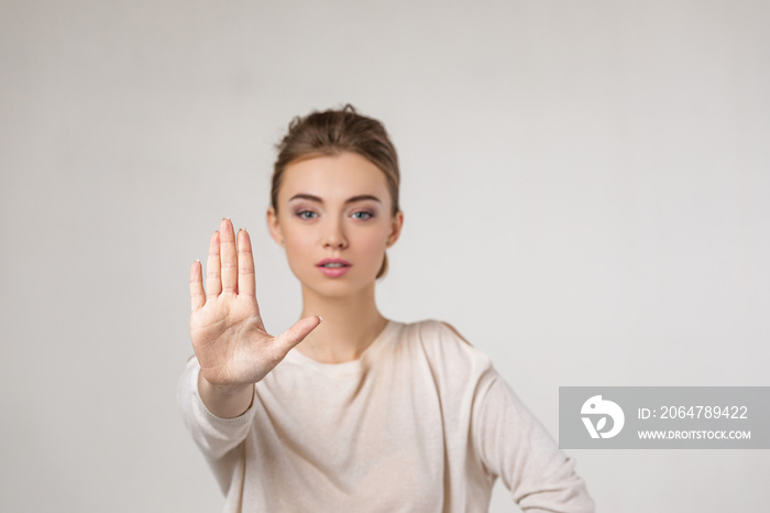 美丽的年轻女子在灰色背景下做出停止手势。