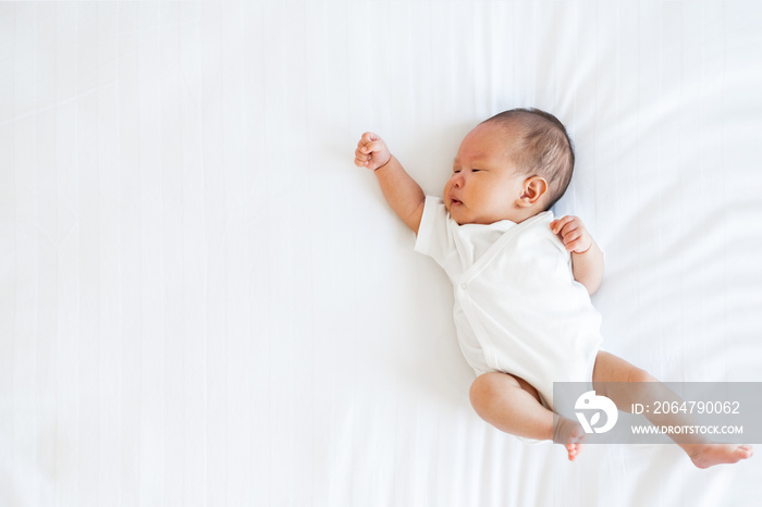 Portrait of Asian newborn baby in white cloth on bed funny pos