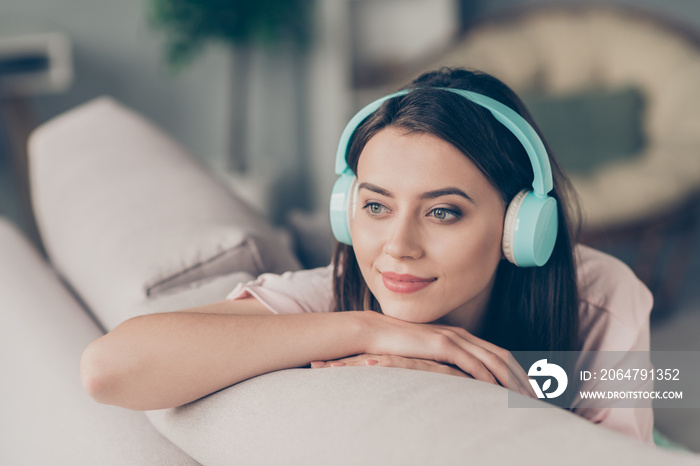 Photo portrait of young girl listening to music wearing cyan headphones sitting on couch lying on ha