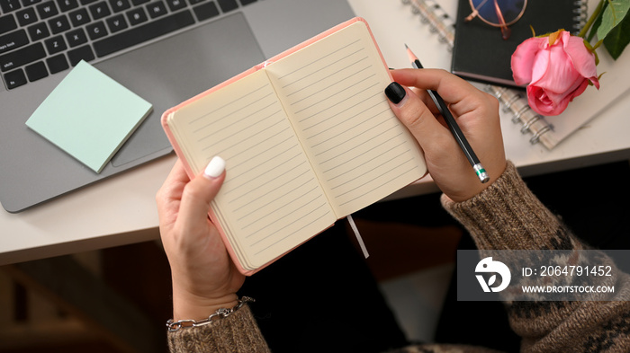 Woman hands in comfort sweater writing on notebook or diary