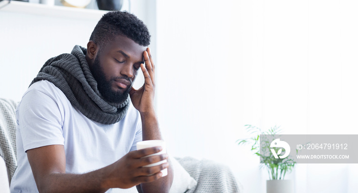 Sad african-american man with flu holding cup with hot tea