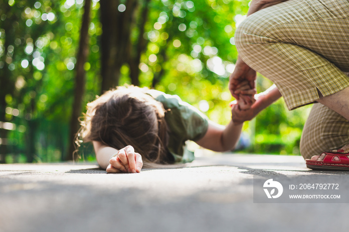 Fainted girl helped by an old woman – Teenager lying on the ground while receiving support from an e